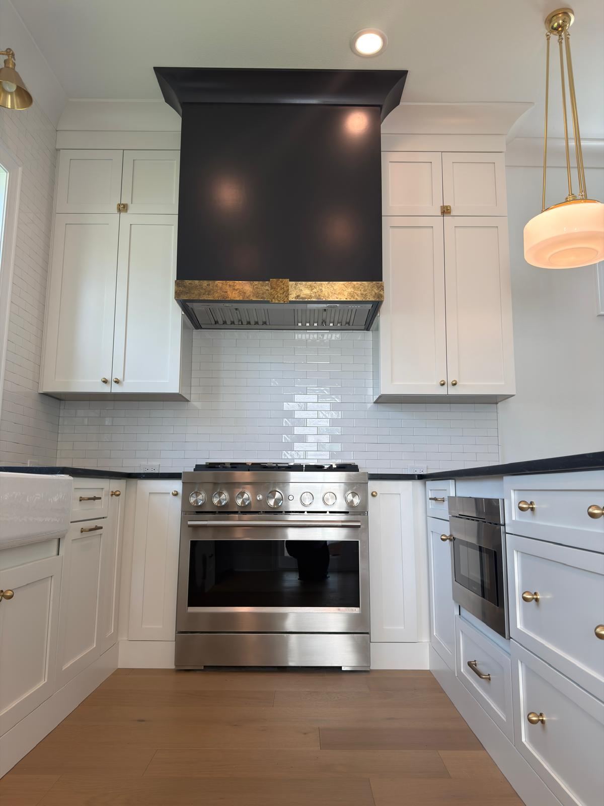 White shaker kitchen with black and brass range hood