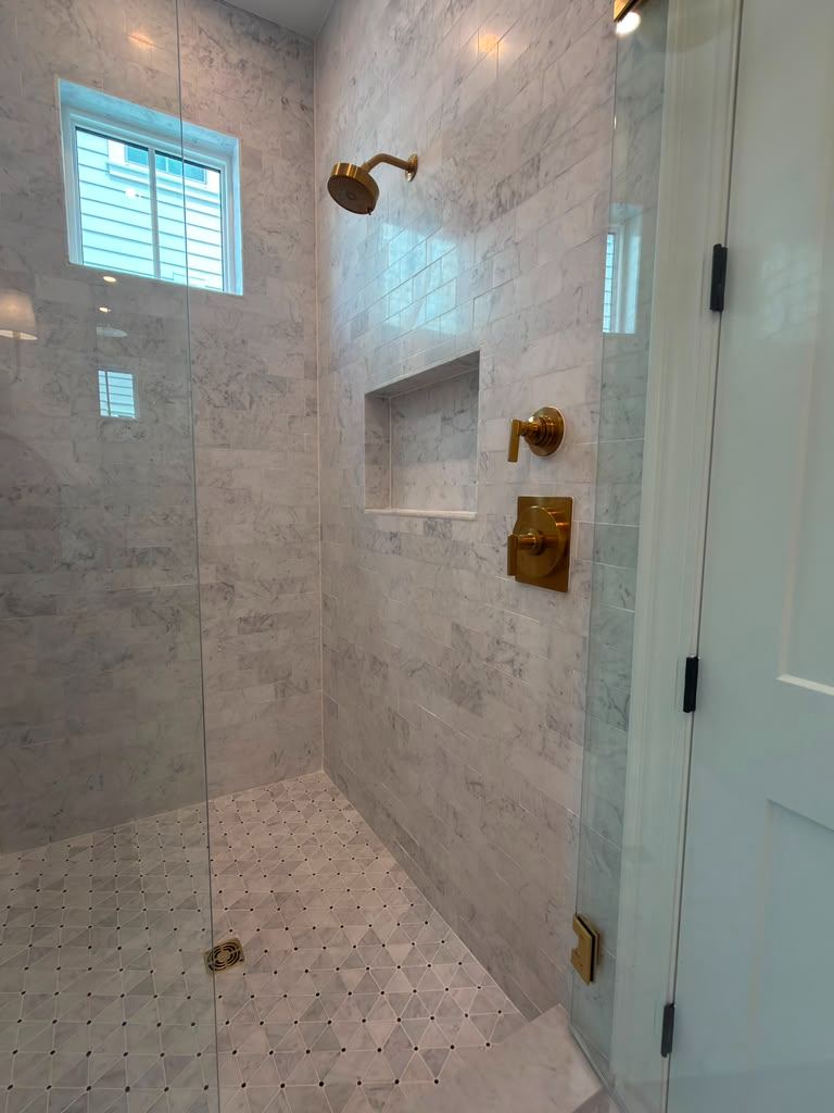 Carrara marble walk-in shower with brass fixtures