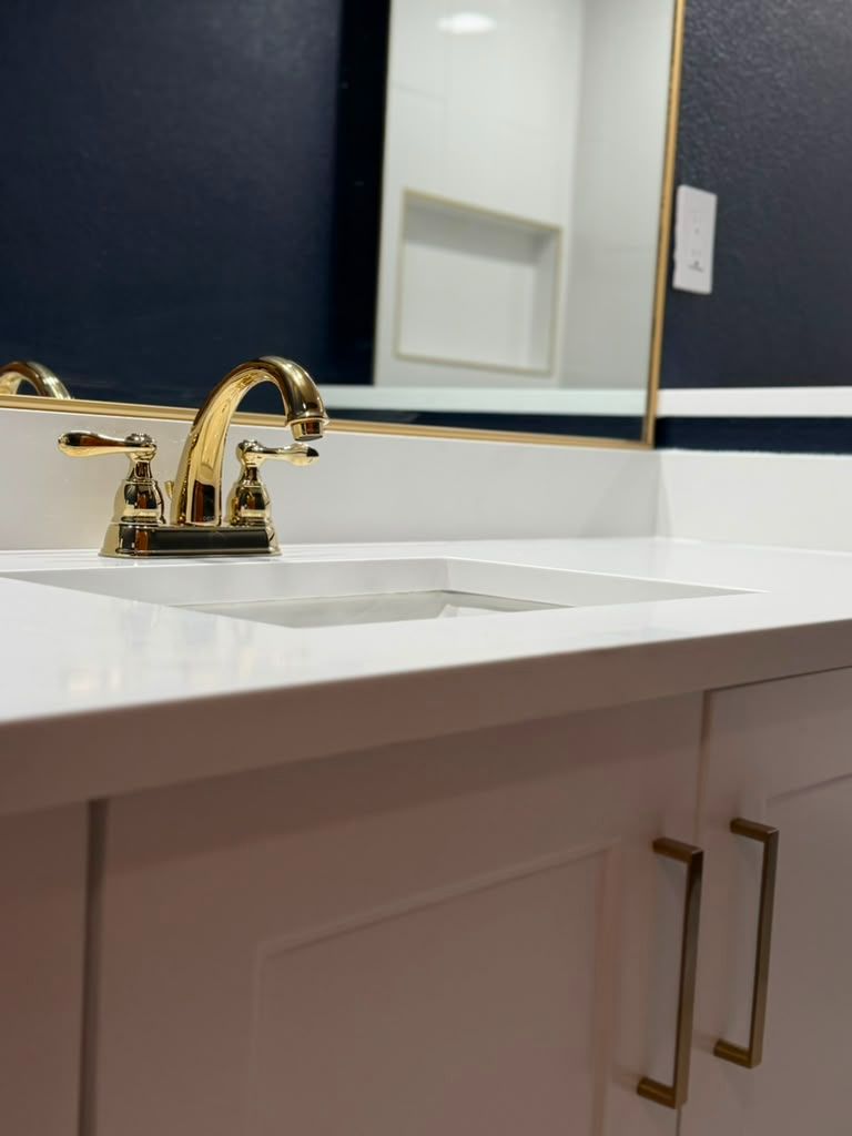 Navy vanity with brass mirrors and marble top