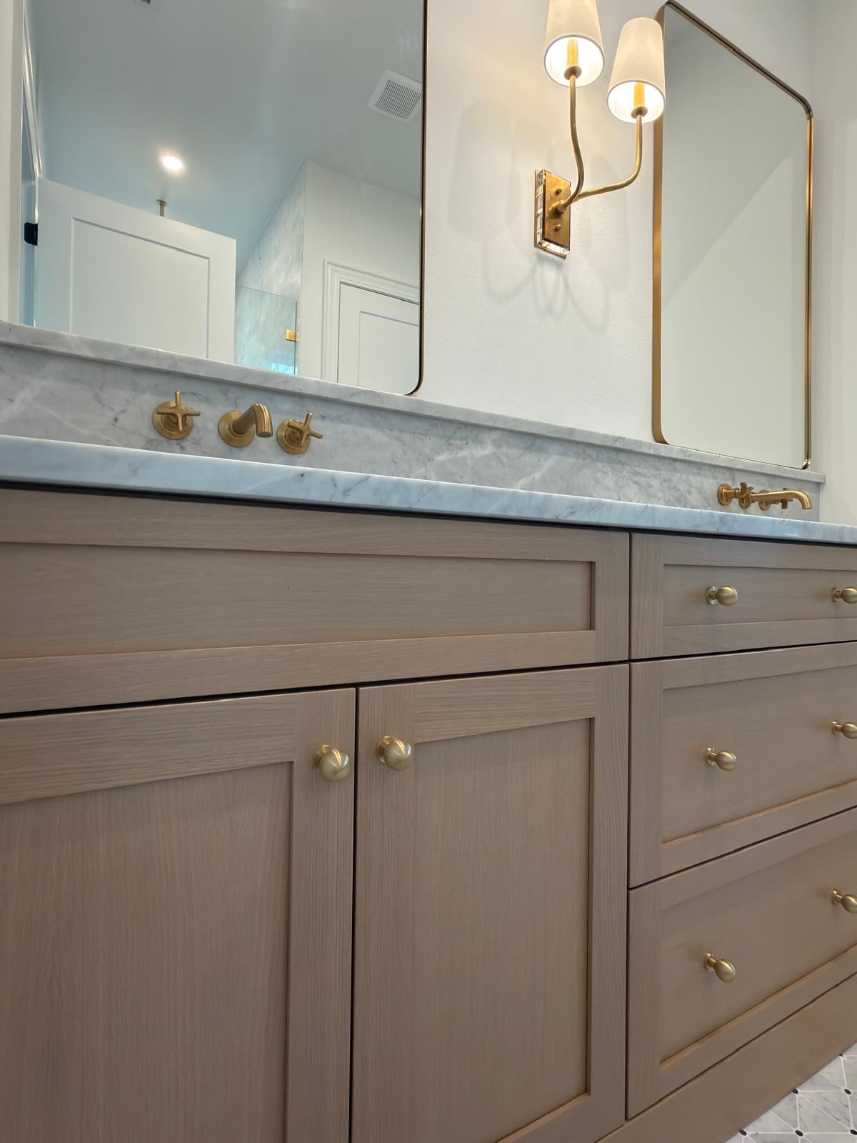 Oak vanity with Carrara marble top and brass wall-mount faucets