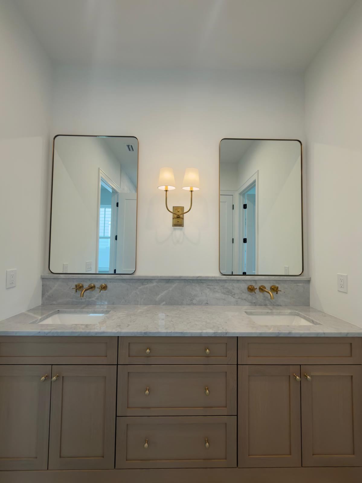 Oak double vanity with marble top and brass sconce