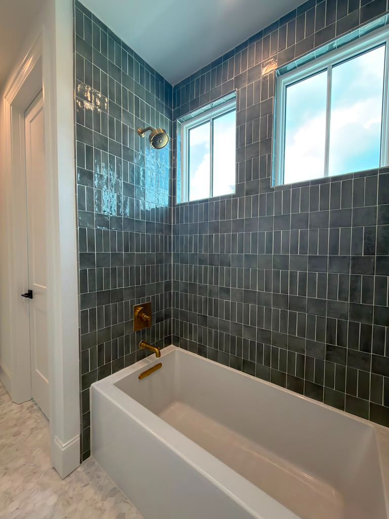 Tub and shower with teal ceramic tile and brass fixtures